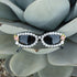 Women's sunglasses with a black frame, decorated with crystal rhinestones and pink flower embellishments.