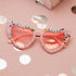 A pair of pink heart-shaped sunglasses with 'BIRTHDAY QUEEN'  multicolored crystals.